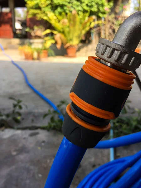 Blue garden water hose nozzle and orange connector.