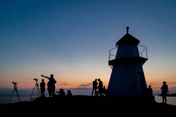 Bua, İsveç - 27 Temmuz 2018: Tam ay tutulmasını görüntülemek ve fotoğraflamak için gün batımından hemen sonra Krogstadsudda deniz fenerinde toplanan küçük kalabalık.