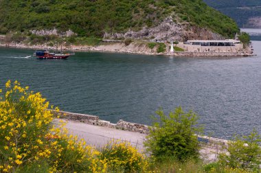 Otantik yat, dağların arka planında koyda Verige 65'i geçiyor.