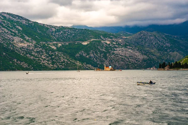 Barco solitario navegando hasta el faro de la Virgen del Acantilado en la Bahía de Kotor . — Foto de Stock