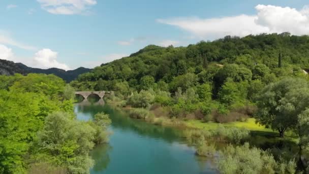 Karadağ'da suya yansıyan Rijeka Crnojevica köyündeki eski köprüye aeral görünümü. Stari en. — Stok video