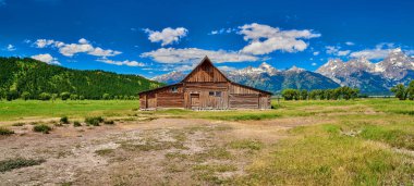 Grand Teton'da Grand Teton dağları ve mavi gökyüzü ile ahır 