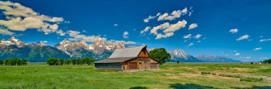 Grand Teton'da Grand Teton dağları ve mavi gökyüzü ile ahır 