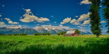 Grand Teton'da Grand Teton dağları ve mavi gökyüzü ile ahır 