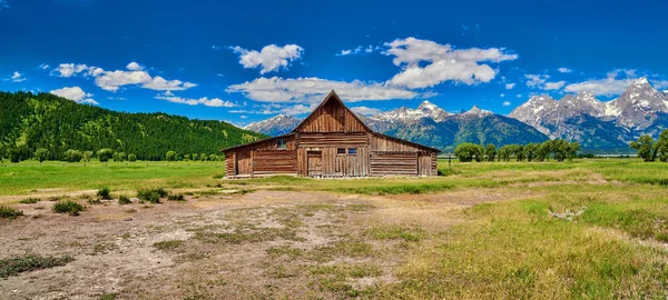 Grand Teton'da Grand Teton dağları ve mavi gökyüzü ile ahır 
