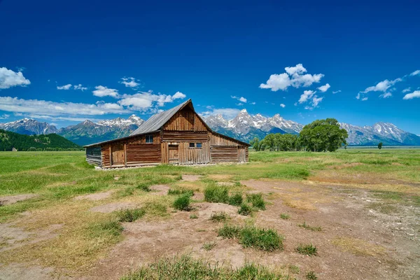 Grand Teton'da Grand Teton dağları ve mavi gökyüzü ile ahır 