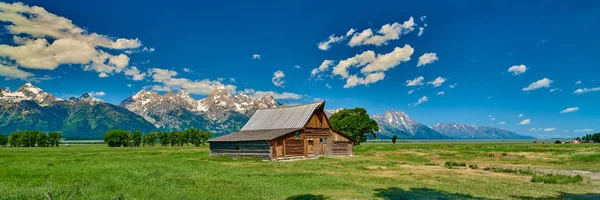 Grand Teton'da Grand Teton dağları ve mavi gökyüzü ile ahır 