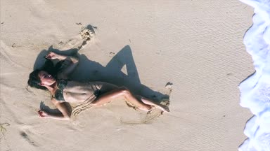 Genç ve çekici bir kadın kumsalda dinleniyor. 