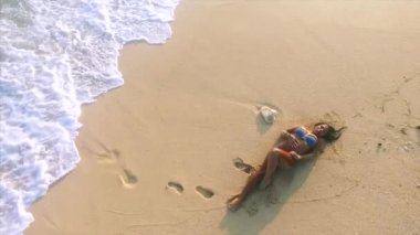 Genç ve çekici bir kadın kumsalda dinleniyor. 