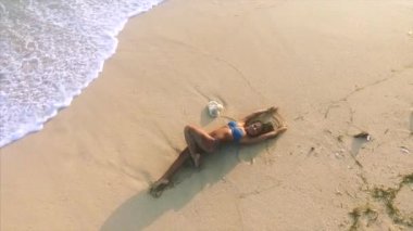 Genç ve çekici bir kadın kumsalda dinleniyor. 