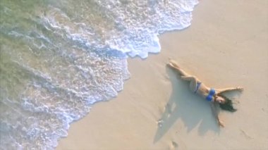 Genç ve çekici bir kadın kumsalda dinleniyor. 