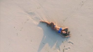 Genç ve çekici bir kadın kumsalda dinleniyor. 