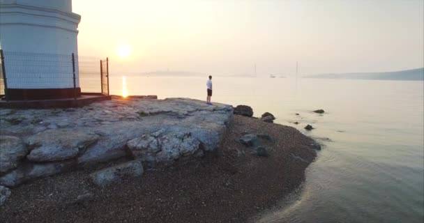 Tokarevsky で早朝に美しい日の出と海の新鮮な空気を楽しむスポーツマンの観点から空中ズーム吐き出す灯台が位置しています ウラジオストク ロシア — ストック動画