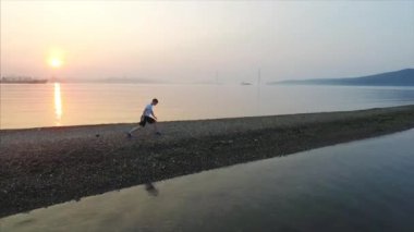 Genç bir adamın Tokarevsky şiş çalıştırmadan önce bacaklarını germe havadan görünümü