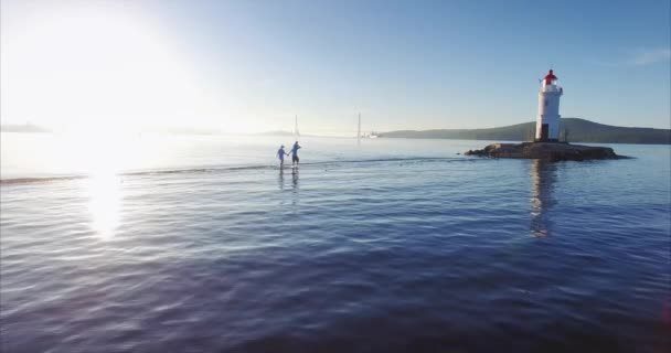 歩いている家族の美しい景色は Tokarevsky 灯台に向かって唾を吐きます 驚くべき海と日の出 肩の上の彼の妻の手と彼の息子を保持しています ウラジオストク 背景には ロシアの橋 — ストック動画