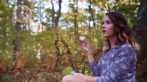 秋の森の木の下で泡を吹いてロマンチックな若い女性の美しい景色 スローモーション — ストック動画