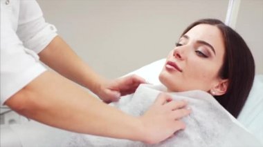Genç çekici kadın Güzellik Kliniği cosmetical yordam için hazır. Güzellik uzmanı tek kullanımlık levha ile istemci koruyor