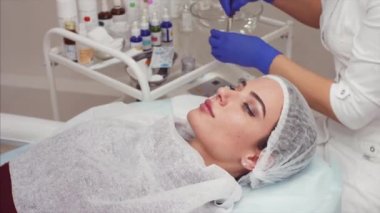 Güzellik salonu güzel genç kadın portresi. Güzellik uzmanı güzellik maskesi küçük kase fırça ile karıştırma hazırlanıyor
