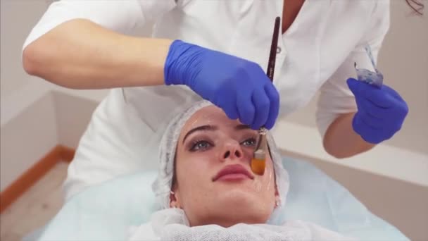美容師は 若い女性の顔の化粧品クリームを入れています 美容クリニック — ストック動画