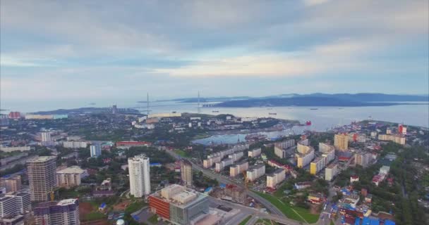 早朝にウラジオストク市内中心部と住宅地の空中ビュー 東ボスポラス海峡をまたぐロシアの橋が背景にあります 夏の日の出 — ストック動画