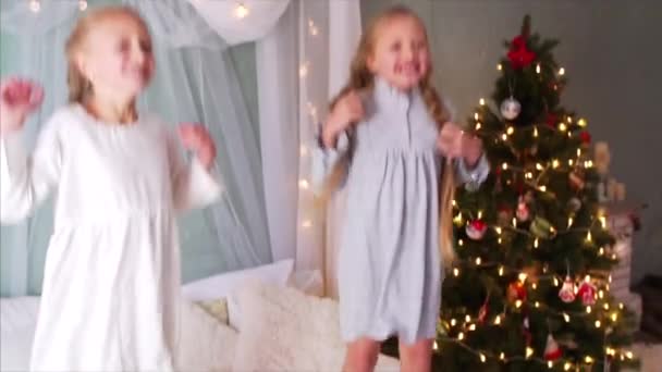 2人の幸せな女の子のゆっくりとした動きは ベッドの上でジャンプし 楽しんでいます クリスマスタイム — ストック動画