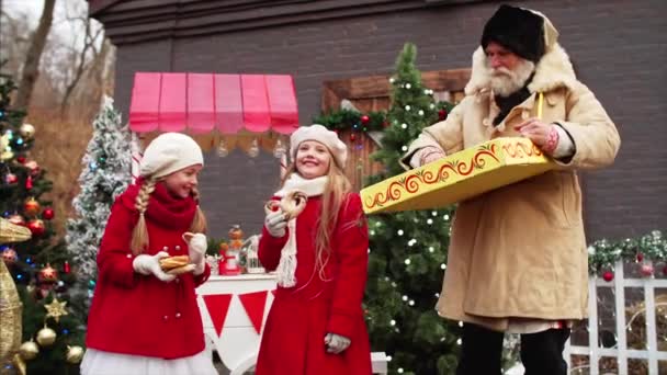 Ein Weißbärtiger Mann Knistert Zwei Mädchen Roten Mänteln Weihnachtsmarkt Schöne — Stockvideo