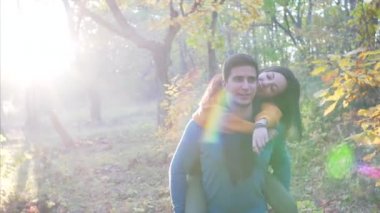 Genç bir kadın, erkek arkadaşıyla güneşli sonbahar ormanlarında gezintiye çıkmış. Konuşuyorlar ve gülümsüyorlar.