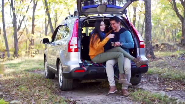 Junges Paar Sitzt Mit Heißem Tee Metallbechern Kofferraum Und Plaudert — Stockvideo