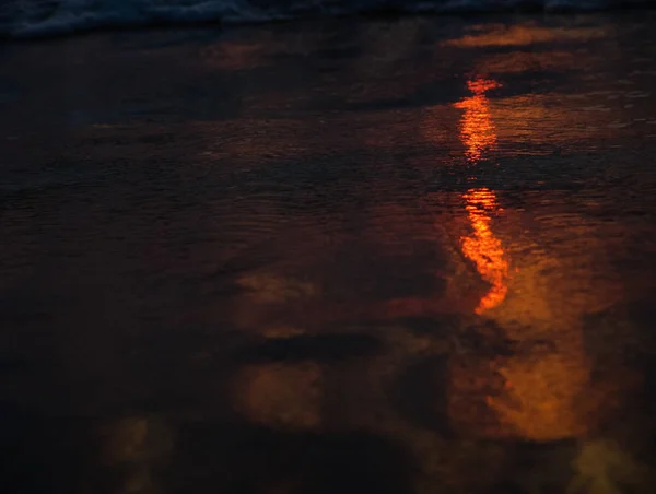 Naranja cálidos reflejos al atardecer sobre una arena mojada en la playa —  Fotos de Stock