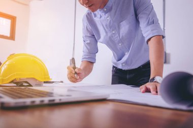 Ofiste masasında inşaat sahasında mimari proje için plan üzerinde çizim çalışma mimarileri