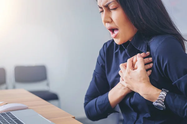 Работающая женщина страдает и держит грудь из-за инфаркта сердца в офисе Стоковое Фото