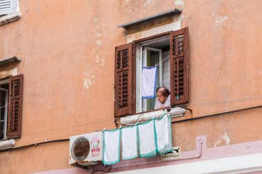 Eylül 2019'da Hırvatistan'ın Rovinj kentinde evine çamaşır yıkdıktan sonra evden bakarken görülen yaşlı bir kadın.