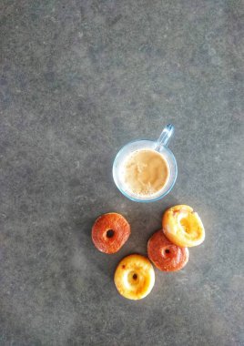 Gri taş arka plan üzerinde kahve ve çörekler ile Fincan