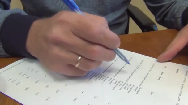 서류를 확인하고 남자가 파란색 잉크로 볼펜이 항목들을 수정하여 클로즈업하고 — 비디오