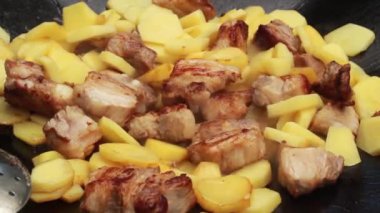 Büyük bir aile ve doğadaki misafirler için yaz güneşli bir günde büyük bir tavada et ve şenlik ateşiyle lezzetli patatesler kızartıyoruz.