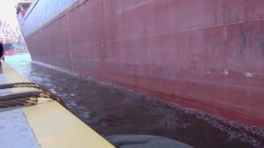 Büyük kuru bir kargo gemisi ticari limana ve rıhtımdaki kırlara giriyor. Rıhtımın manzarası. Yakın plan.