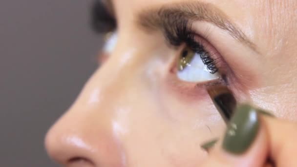 Een Schoonheidssalon Brengt Een Professionele Schoonheidsspecialiste Eyeliner Aan Het Onderste — Stockvideo