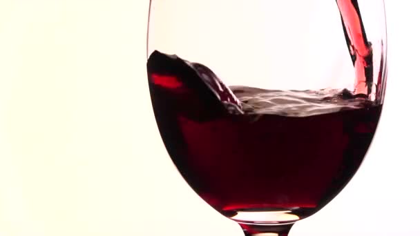 Red wine poured into glass on white background — Stock Video