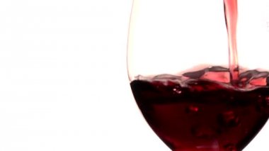 Kırmızı şarap cam içine beyaz zemin üzerine dökülür.