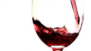 Kırmızı şarap cam içine beyaz zemin üzerine dökülür.