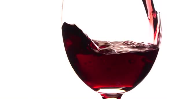 Красное вино налито в бокал на белом фоне — стоковое видео