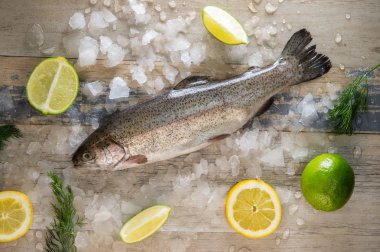 Hazırlanması alabalık, dilimlenmiş limon ve yeşil biberiye. Yemek yemek bir ahşap tahta üzerinde