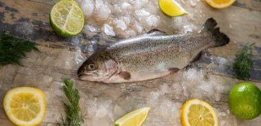 Hazırlanması alabalık, dilimlenmiş limon ve yeşil biberiye. Yemek yemek bir ahşap tahta üzerinde