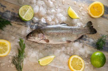 Hazırlanması alabalık, dilimlenmiş limon ve yeşil biberiye. Yemek yemek bir ahşap tahta üzerinde