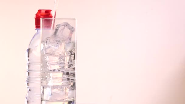 Garrafa e vidro de água com cubos de gelo na plataforma giratória — Vídeo de Stock