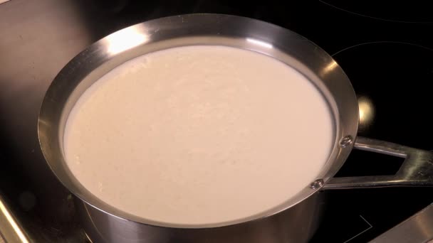 Готовить натуральное органическое молоко, варить молоко в горшках, молоко, которое вот-вот переполнится, переполненное молоко — стоковое видео