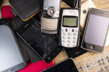 Ahşap arka planda eski, kırık ve eski cep telefonu