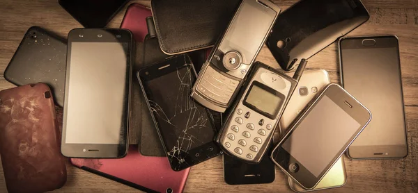 Старый, сломанный и устаревший мобильный телефон на деревянном фоне — стоковое фото