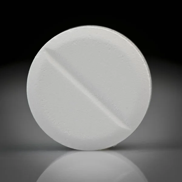 Fehér tabletta forog-ra egy fekete háttér, makró lövés — Stock Fotó