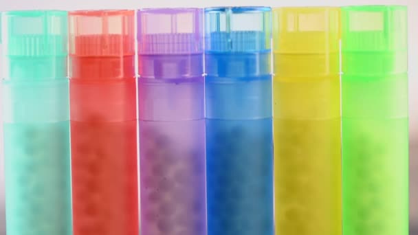 Moderne kleur homeopathische pillen in plastic container op zwarte achtergrond — Stockvideo